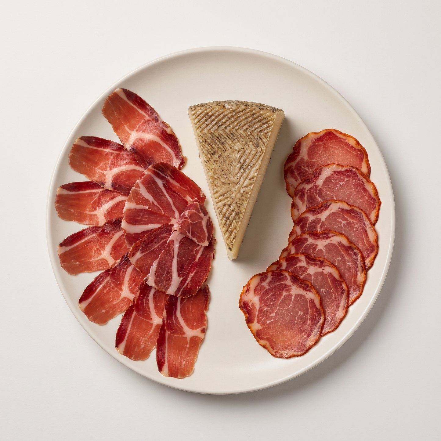 Bellota Charcuterie Selection — Jamón Ibérico, Lomo, and Manchego cheese plated with rosemary sprig and wooden spoon on linen