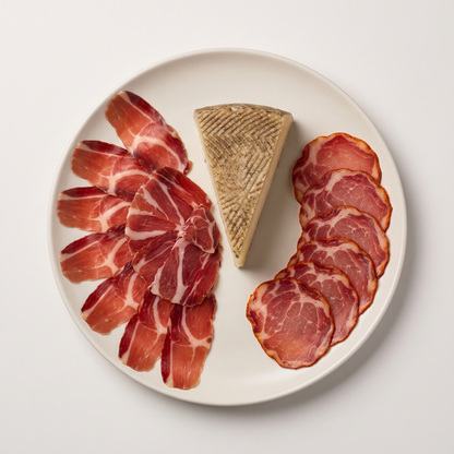 Bellota Charcuterie Selection — Jamón Ibérico, Lomo, and Manchego cheese plated with rosemary sprig and wooden spoon on linen